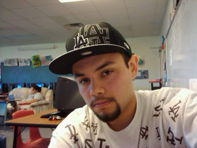 Younger Michael in a baseball cap and an LA-monogrammed shirt, indoors.